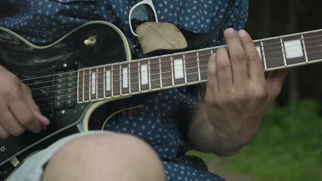 Man is playing at the electric guitar in forest