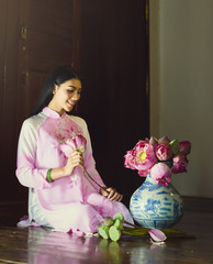 Portrait of Vietnam girls with Ao Dai preparing flower, lotus in jug.