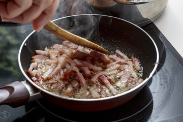 Mamá friendo beicon en casa.