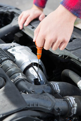 Fototapeta na wymiar Checking Car Engine Oil Level Under Hood With Dipstick
