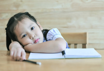 sweet sad  little asian school girl looking bored and tired in stress with books and homework in children education concept isolated on uniform student girl  notebook