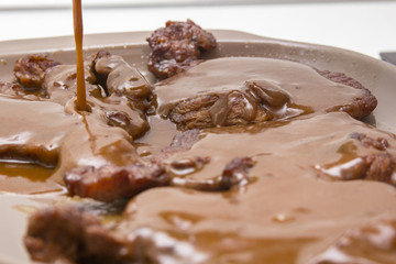 Mamá preparando en casa unas chuletas con salsa de cebolla caramelizada.