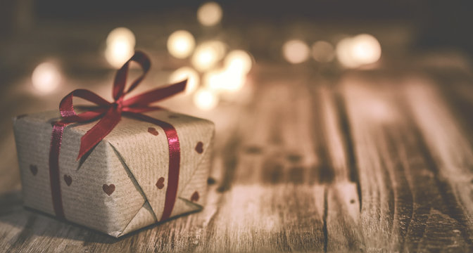 Kleines Weihnachtsgeschenk mit Lichtpunkten vor Holz