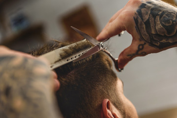 Obraz premium scissors and comb in hands of barber