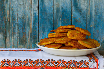 Potato pancakes on an embroidered napkin, blue wood background
