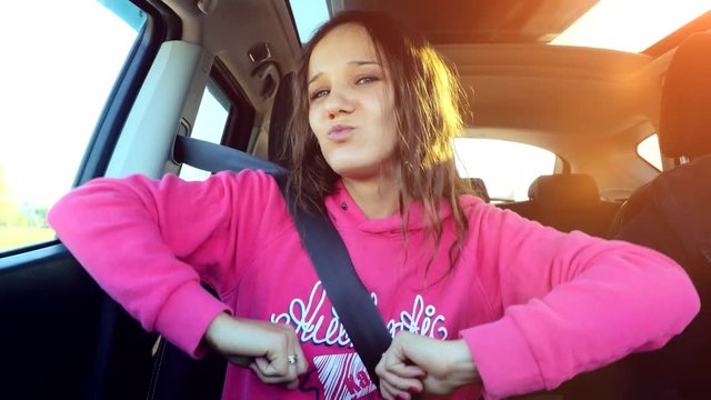 Teen beautiful girl sings and dances in the car on the sunshine background during sunset. 3840x2160
