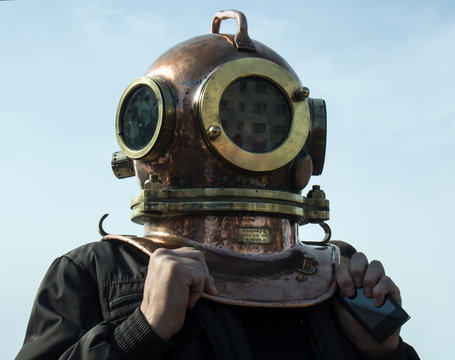 Man stands in his head to put on an old diving helmet