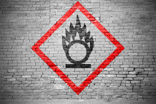 Ziegelsteinmauer mit GHS-Piktogramm Brandf&ouml;rdernd Graffiti
