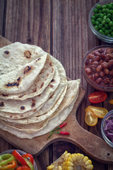 Mexican corn tortilla tacos with vegetables on wooden background 