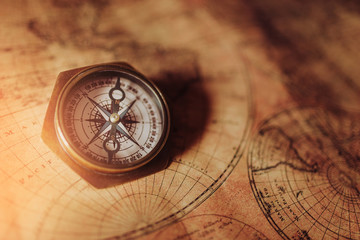 Close up of an old nautical compass on vintage map with sunshine
