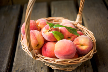 Basket of ripe peaches against a wooden background
