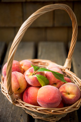 Basket of ripe peaches against a wooden background