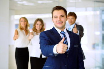 Obraz premium Smiling businessman in office with colleagues in the background