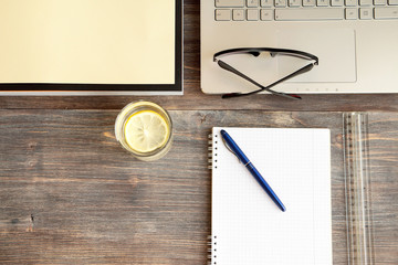 Concept of intellectual work - notebook computer, pen, notebook paper, book and healthy lemon...