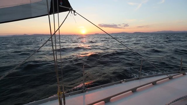 Sailing in the wind through the waves during sunset. Boat shot in full HD at Aegean Sea. Cruise luxury yachting.