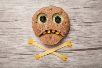 Halloween skull made of bread and vegetables on wooden background