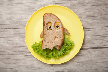 Halloween ghost made of bread and salad on plate and desk