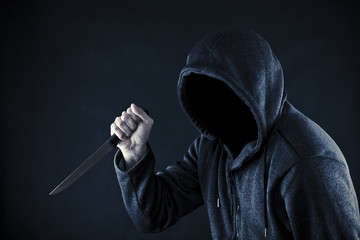 Hooded man with knife in the dark