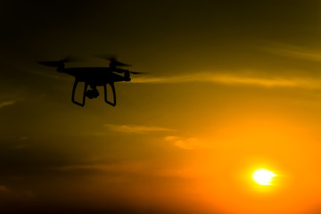 Quadrocopters silhouette against the background of the sunset. Flying drones in the evening sky