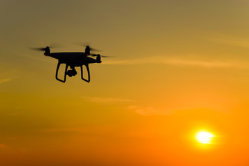 Quadrocopters silhouette against the background of the sunset. Flying drones in the evening sky