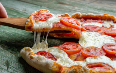Slice pizza on wood skimmer.