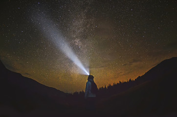 Woman is standing in the forest and pointing the Milky Way ,Carpathian ,Ukraine