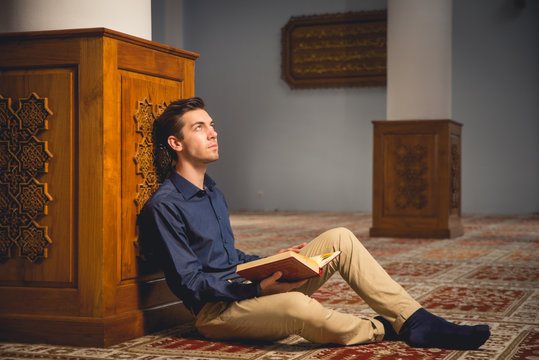 Young Muslim man praying in a mosque.