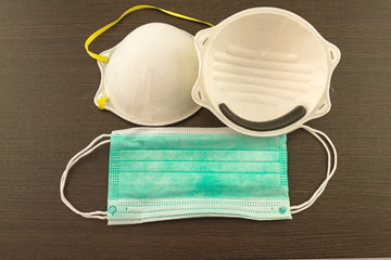 Close up of white mask and blue surgical mask stack on black wooden background