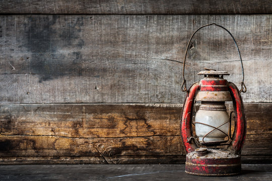 Old fashioned vintage kerosene oil lantern lamp burning with a soft glow light with aged wooden floor with copy space