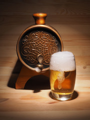 Barrel and glass of light beer on a wooden background
