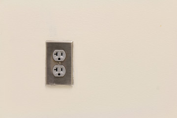 Silver metal outlet cover on white wall
