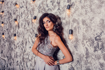 Gorgeous portrait of a stunning woman in silk grey dress sitting