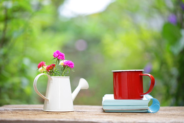 Red mug with flower and notebooks on wooden table