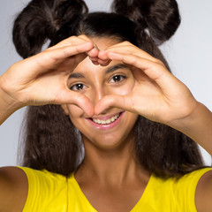 Emotional young brunette girl with long hair in yellow shirt on a white background