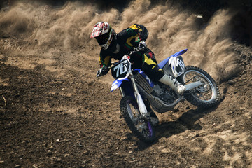 Motocross rider creates a large cloud of dust and debris