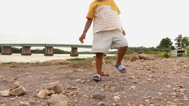 Cute asian little boy playing with stone near river