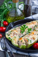 Zucchini boats stuffed with ground meet on cast iron pan