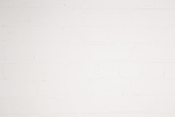 Uneven lighting on the white painted brick wall. Background. Focus point in the center.
