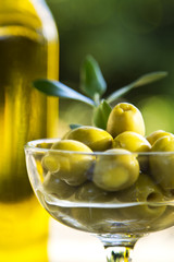 glass cup filled with olives and olive oil bottles © tetxu