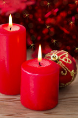 lit candles and Christmas balls on red background