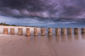 Baltic sea coast on cloudy evening with wooden groyne, Poland