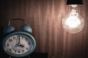 bulb and clock on wooden background