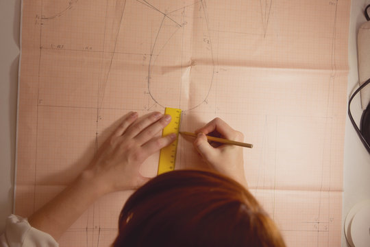 seamstress draws the pattern on graph paper in the studio