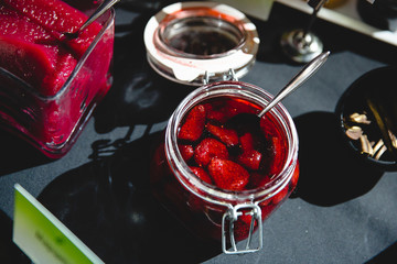 Jelly made of strawberries in a glass bowl stands on the black t