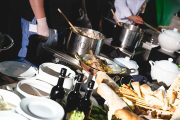 Cooks stands behind tables and stoves making a dinner