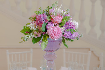 Tender pink bouquet stands on a high violet glass vase