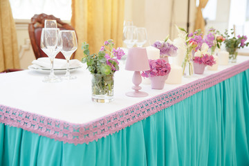 Pink bouquets and lamps beautify a dinner table for two persons