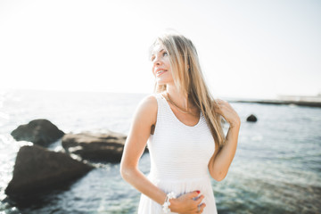 portrait of young woman posing near sea, wearing a dress
