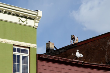 Fototapeta na wymiar Man on rooftop making repairs
