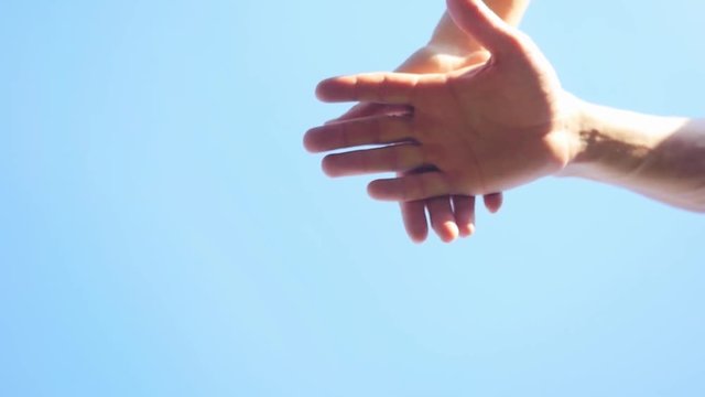 Successful team: many hands holding together on sky background in slowmotion. 1920x1080
